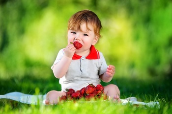 坐在草地上吃草莓的小孩