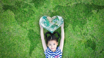 举着一颗心躺在草地上的小女孩