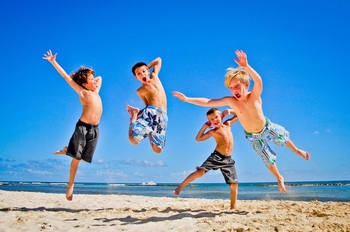 在沙滩上兴奋跳起的男孩子们
