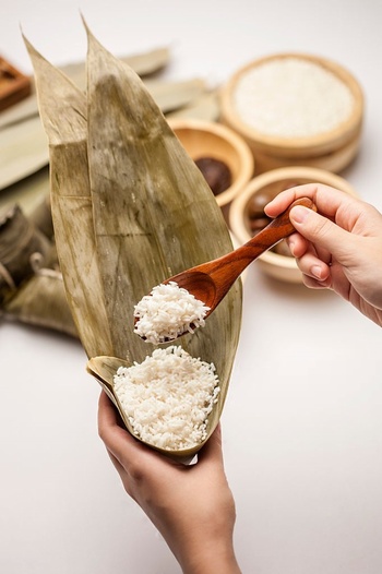 包粽子用勺子把米放进粽叶里