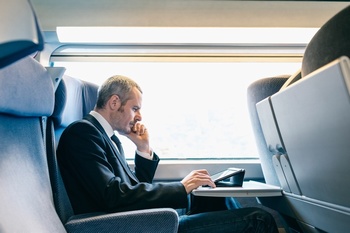 一个商务男士在动车上看平板电脑