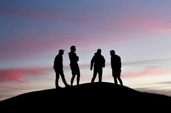 黄昏时分山顶上四个男士的剪影