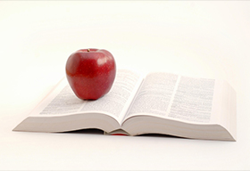 一本厚書上放著的紅蘋果